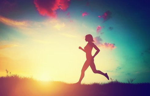 Silhouette of a fit woman running at sunset