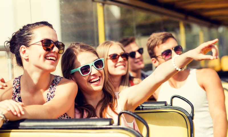 Grupo de amigos sonrientes que viajan en un autobús turístico
