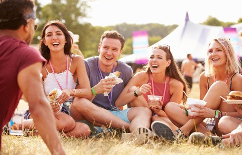 Friends sitting on grass and eating at music festival